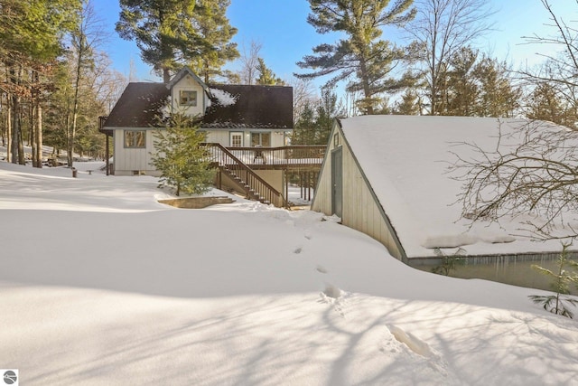 view of snow covered exterior with a deck and stairway