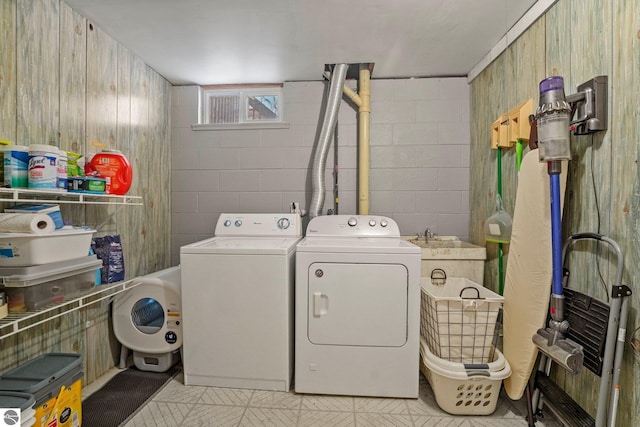 washroom featuring concrete block wall, laundry area, and independent washer and dryer