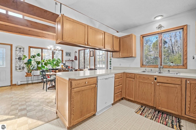 kitchen featuring dishwasher, a peninsula, a sink, and light countertops