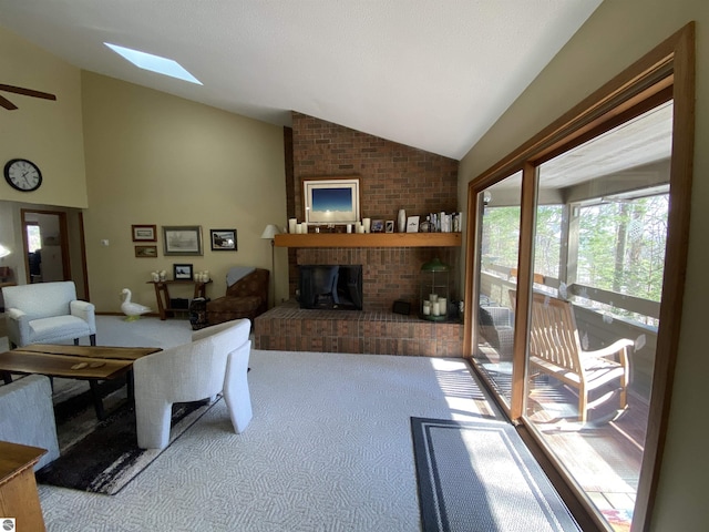 living room with carpet, vaulted ceiling with skylight, ceiling fan, and a brick fireplace