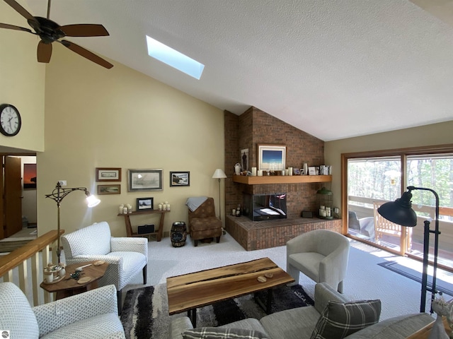 carpeted living area with lofted ceiling with skylight, ceiling fan, a brick fireplace, and a textured ceiling