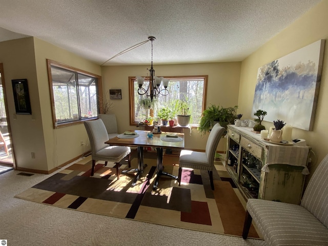 dining area featuring carpet floors, a notable chandelier, visible vents, a textured ceiling, and baseboards