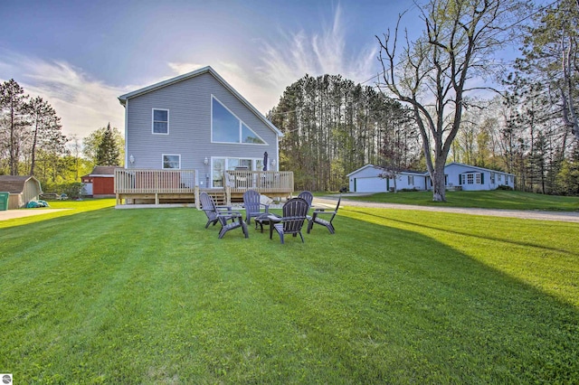 rear view of property featuring a deck, a lawn, an outdoor structure, and a storage shed