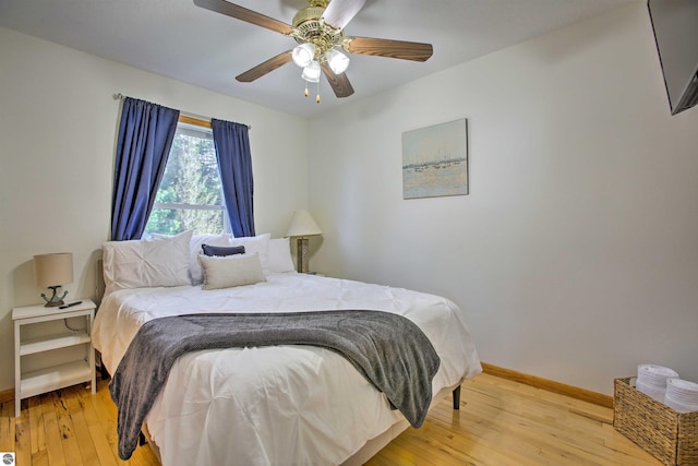 bedroom featuring baseboards, light wood-style floors, and a ceiling fan