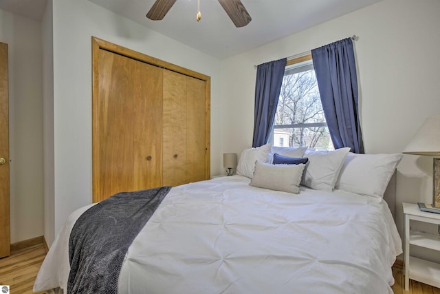 bedroom with a closet, light wood finished floors, a ceiling fan, and baseboards