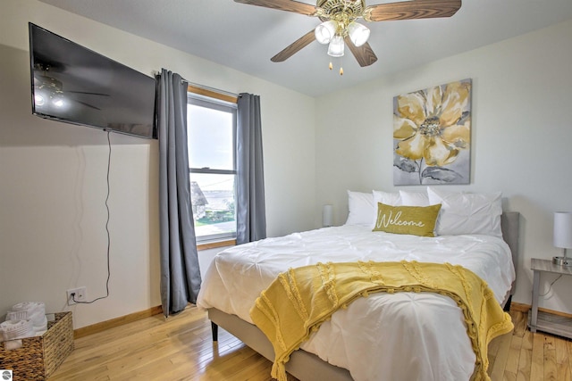 bedroom with light wood finished floors, a ceiling fan, and baseboards