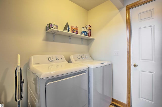 laundry area with laundry area, washing machine and dryer, and baseboards