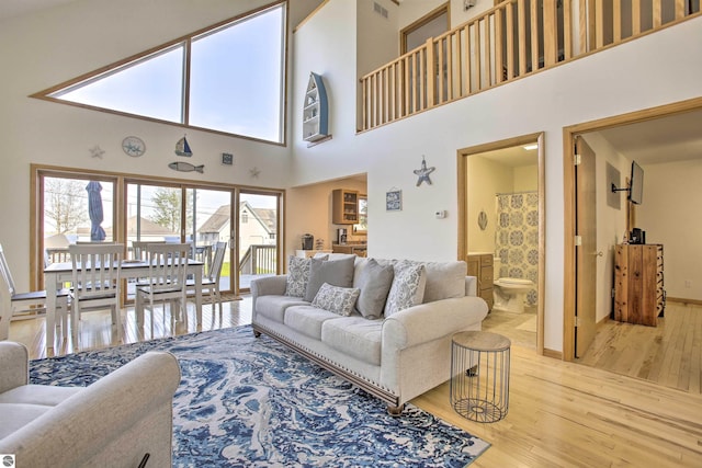 living room with baseboards, wood finished floors, and a towering ceiling