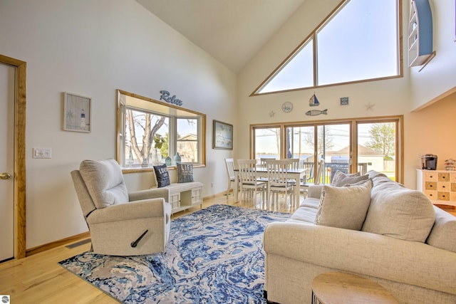 living area featuring visible vents, high vaulted ceiling, baseboards, and wood finished floors