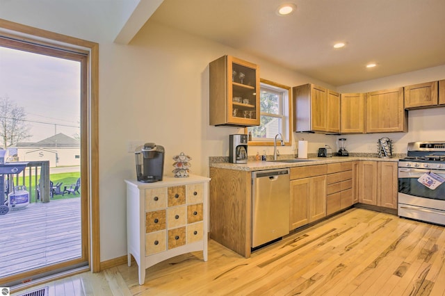 kitchen featuring a sink, stainless steel appliances, light wood-type flooring, and light countertops