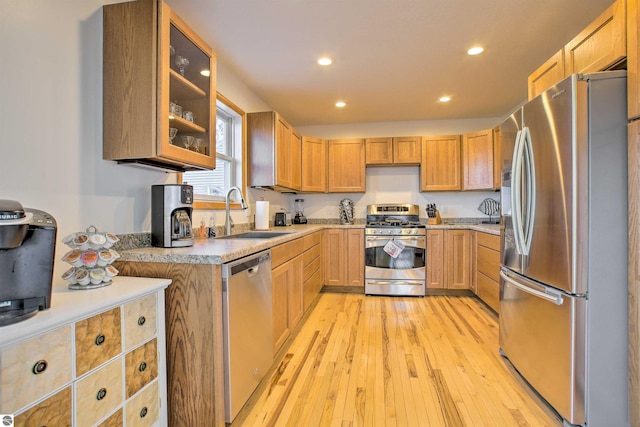 kitchen featuring a sink, stainless steel appliances, light wood-style floors, and light countertops