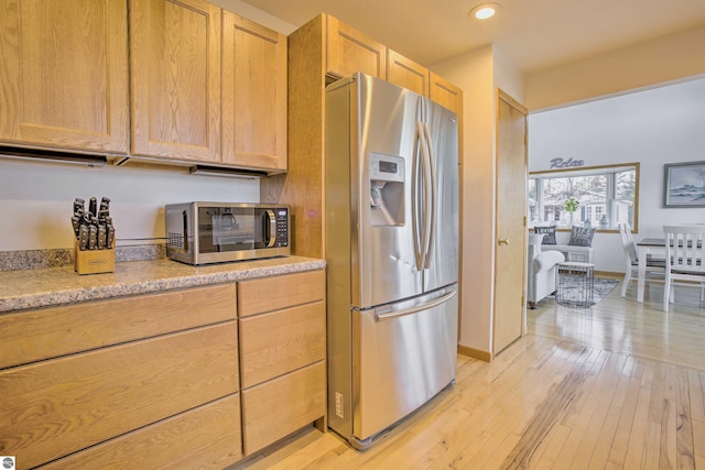 kitchen featuring light brown cabinets, baseboards, recessed lighting, stainless steel appliances, and light wood-type flooring