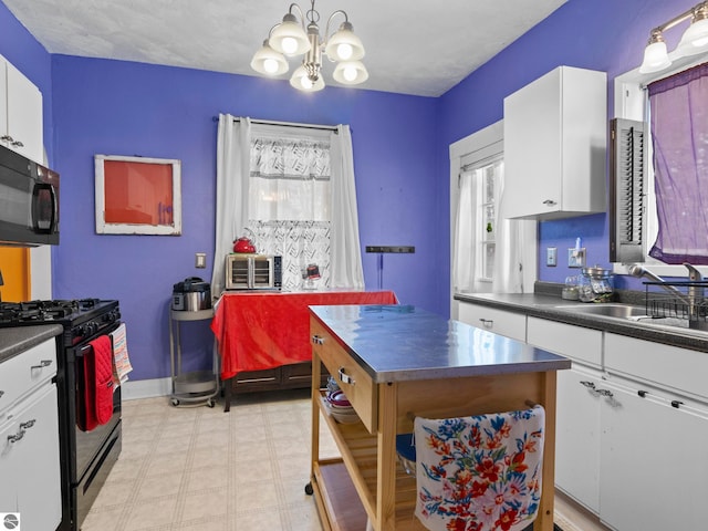 kitchen with black appliances, dark countertops, a sink, and white cabinets