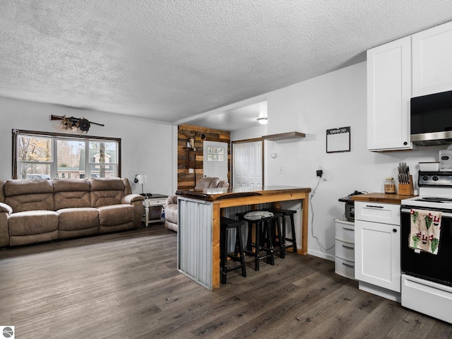 kitchen with electric range oven, stainless steel microwave, dark wood-style floors, and white cabinetry