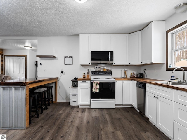 kitchen with dark wood finished floors, appliances with stainless steel finishes, a sink, and butcher block counters