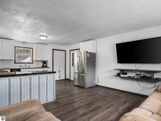 kitchen featuring white cabinets, dark wood finished floors, a sink, and freestanding refrigerator