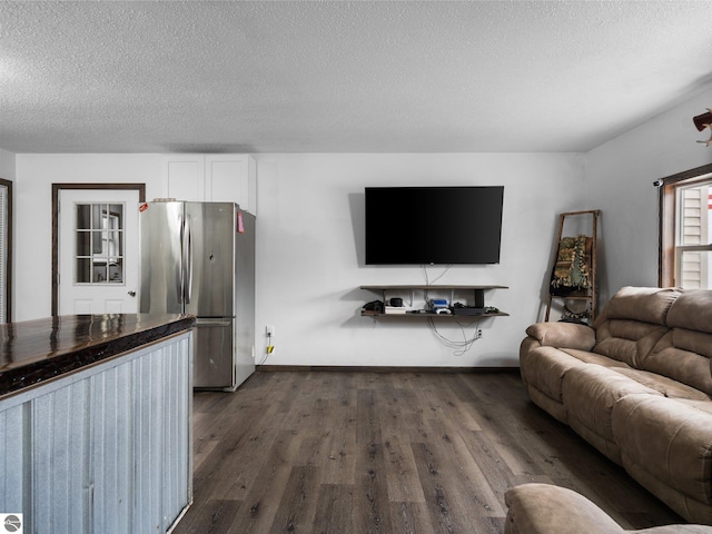 living room featuring a textured ceiling, dark wood finished floors, and baseboards