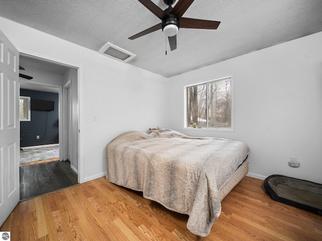 bedroom featuring a textured ceiling, wood finished floors, attic access, and baseboards