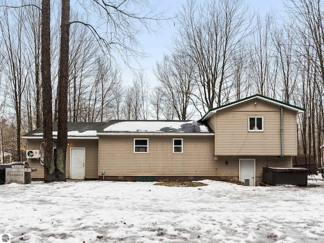 snow covered rear of property featuring a jacuzzi