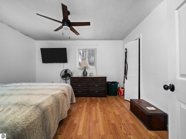 bedroom with ceiling fan, light wood-style flooring, and a textured ceiling