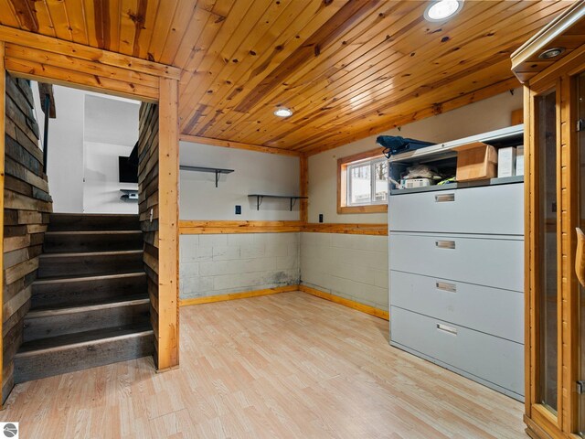 basement with light wood-type flooring, wood ceiling, and stairway