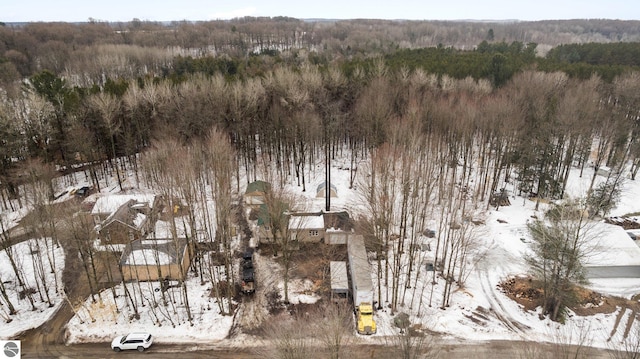 snowy aerial view with a wooded view