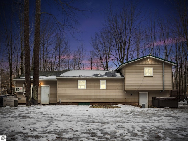 snow covered rear of property featuring a jacuzzi