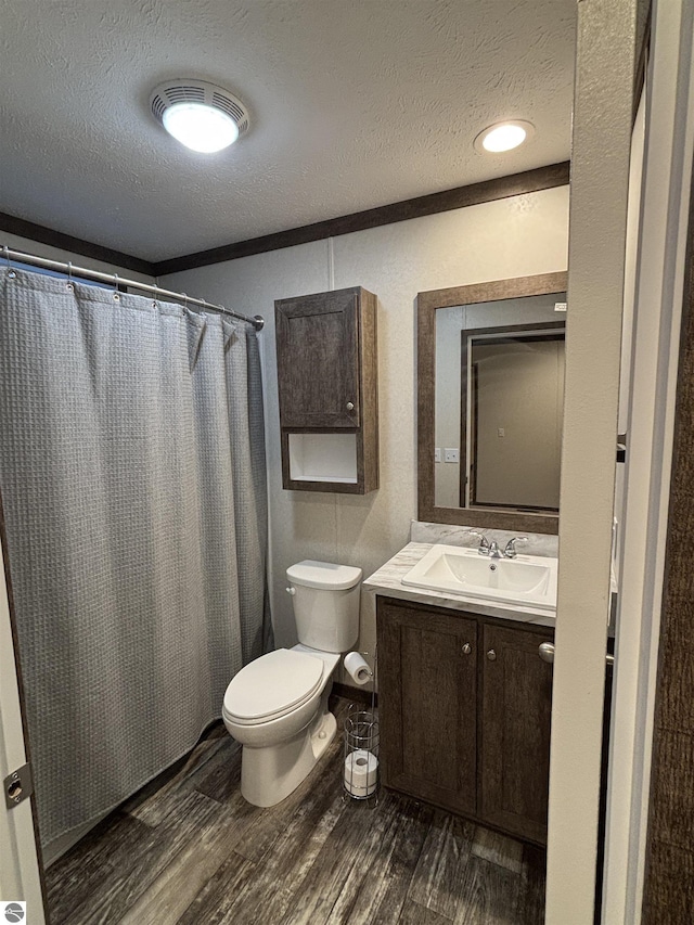 full bathroom with a textured ceiling, curtained shower, toilet, wood finished floors, and vanity