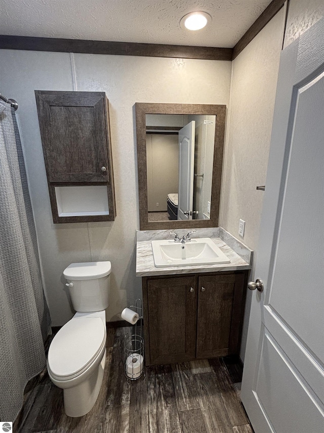 bathroom with toilet, vanity, a textured ceiling, wood finished floors, and a shower with curtain