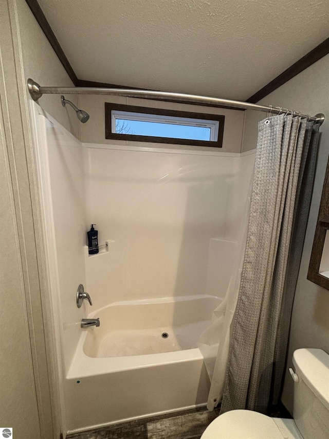 bathroom featuring toilet, shower / bath combination with curtain, and a textured ceiling