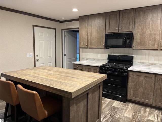 kitchen with visible vents, wooden counters, light wood-style flooring, dark brown cabinetry, and black appliances