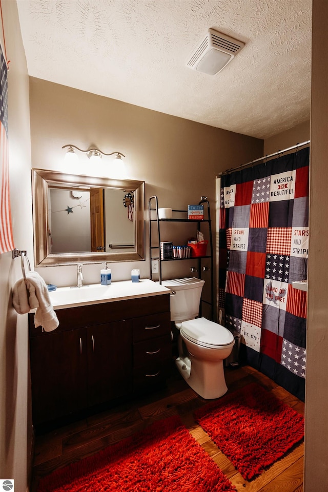 bathroom with toilet, visible vents, a textured ceiling, and vanity