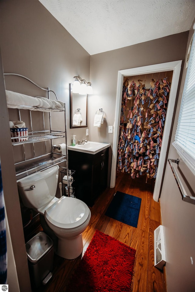 bathroom with a textured ceiling, vanity, wood finished floors, and toilet