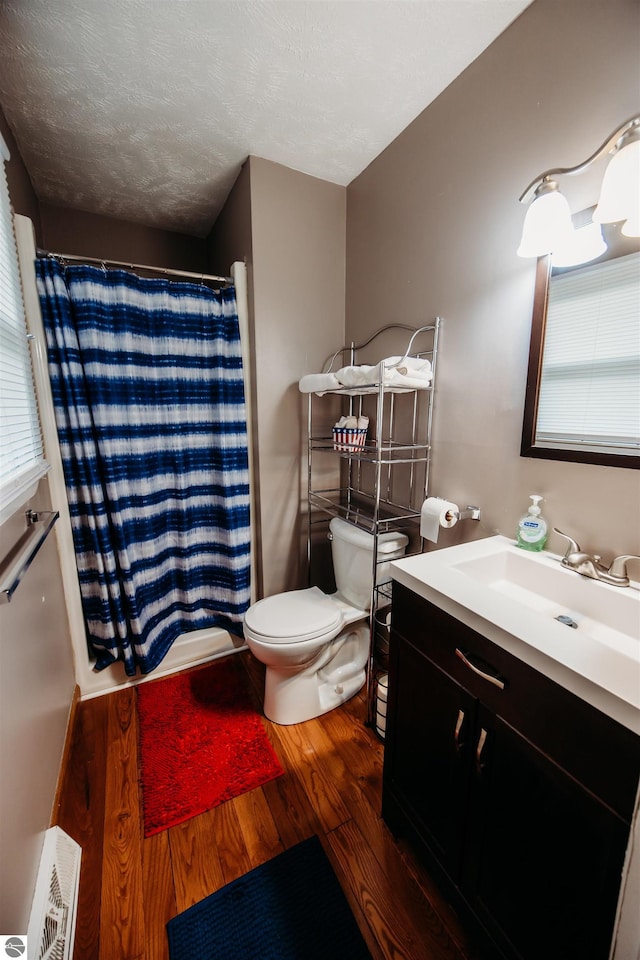 full bath featuring toilet, a shower with curtain, wood finished floors, a textured ceiling, and vanity