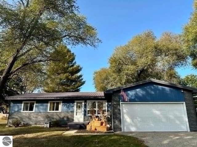 ranch-style house featuring a garage, driveway, and metal roof