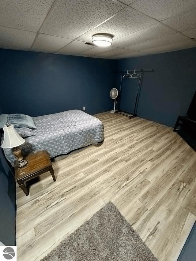 bedroom featuring a drop ceiling and wood finished floors