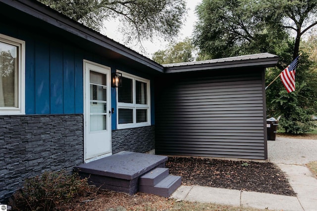 entrance to property featuring metal roof and stone siding