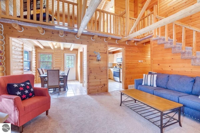 carpeted living room featuring log walls, visible vents, stairway, a towering ceiling, and tile patterned floors