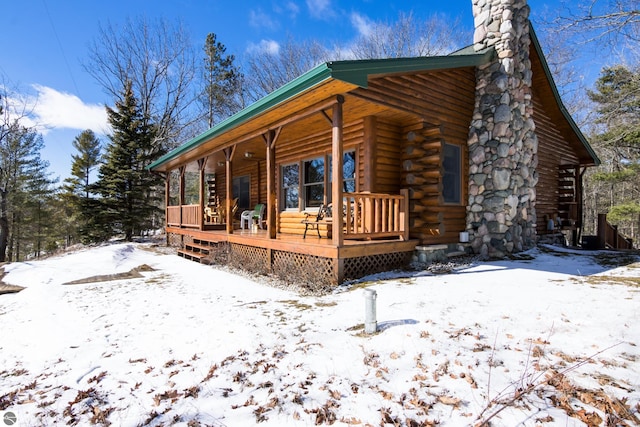 view of front of home with log exterior, a porch, and a chimney