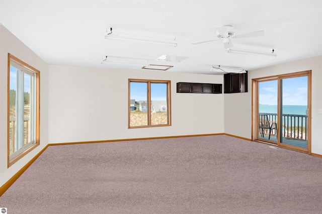 unfurnished room featuring a healthy amount of sunlight, carpet floors, and baseboards