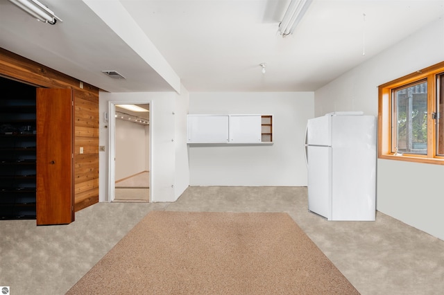 spare room featuring wood walls, visible vents, and light colored carpet