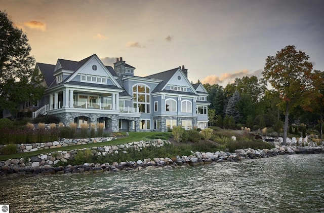 rear view of house with stone siding and a water view