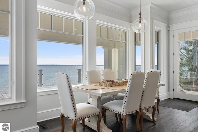 dining area with dark wood-style floors, visible vents, a water view, and ornamental molding