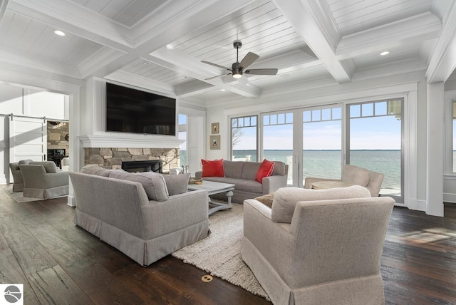 living area with a stone fireplace, crown molding, beamed ceiling, and dark wood-style flooring