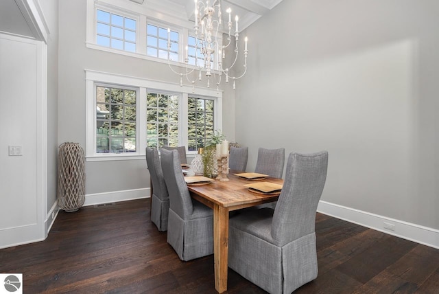 dining area featuring dark wood-style floors, an inviting chandelier, a high ceiling, and baseboards