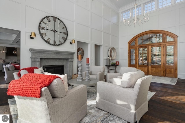 living room featuring a chandelier, a decorative wall, a glass covered fireplace, and ornamental molding