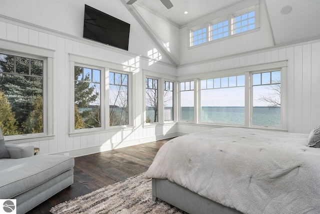 bedroom with a high ceiling, wood finished floors, and a water view