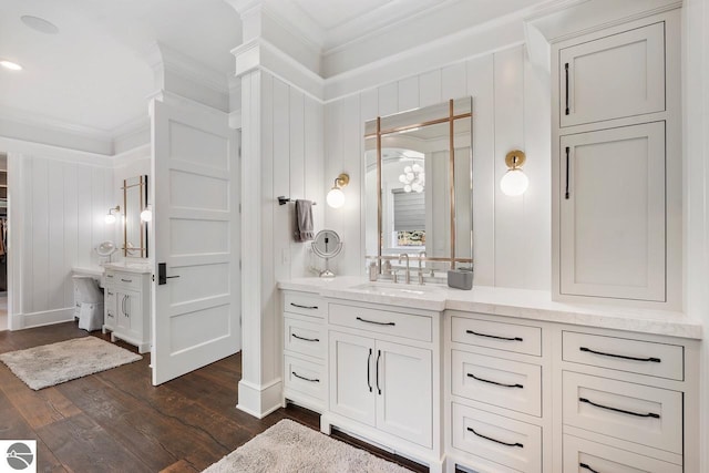 bathroom featuring baseboards, vanity, wood finished floors, and crown molding