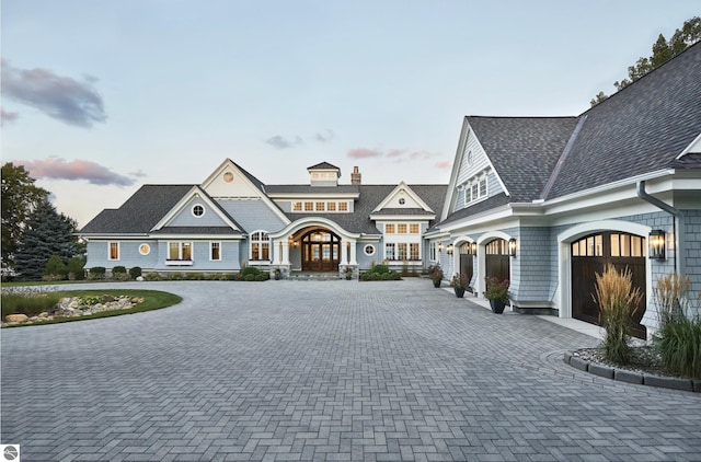 shingle-style home featuring decorative driveway and a garage