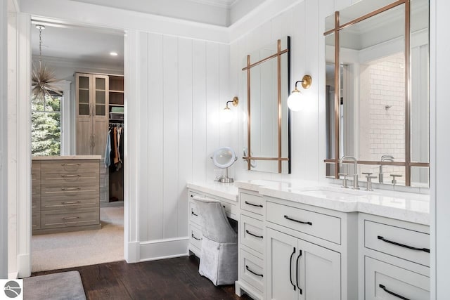 full bath featuring a walk in closet, wood finished floors, crown molding, baseboards, and vanity